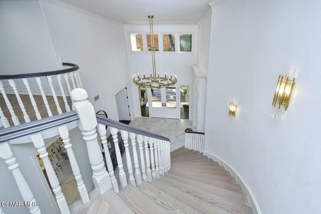 stairs featuring french doors, a chandelier, and ornamental molding