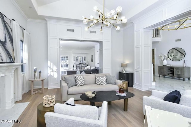 living room with a notable chandelier, light hardwood / wood-style floors, a fireplace, and ornamental molding