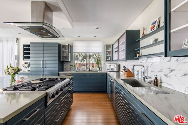 kitchen with tasteful backsplash, island exhaust hood, stainless steel appliances, and blue cabinets