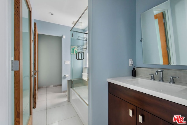 bathroom with tile patterned flooring, vanity, and bath / shower combo with glass door