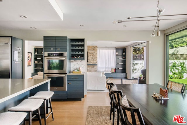 kitchen with a kitchen bar, appliances with stainless steel finishes, and light hardwood / wood-style flooring