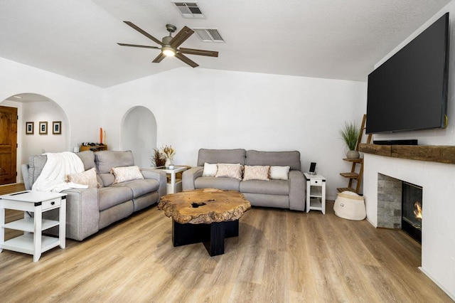 living room with light wood-type flooring, ceiling fan, and vaulted ceiling