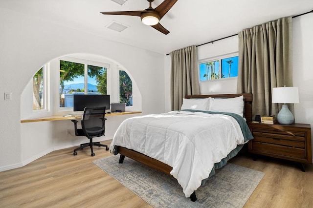 bedroom with ceiling fan, light hardwood / wood-style flooring, and built in desk