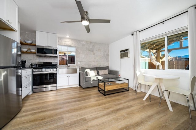 kitchen with sink, white cabinets, ceiling fan, light hardwood / wood-style flooring, and appliances with stainless steel finishes