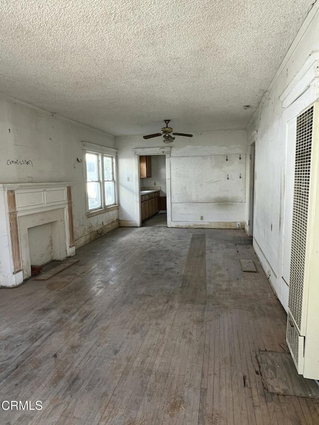 unfurnished living room featuring wood-type flooring, a textured ceiling, and ceiling fan