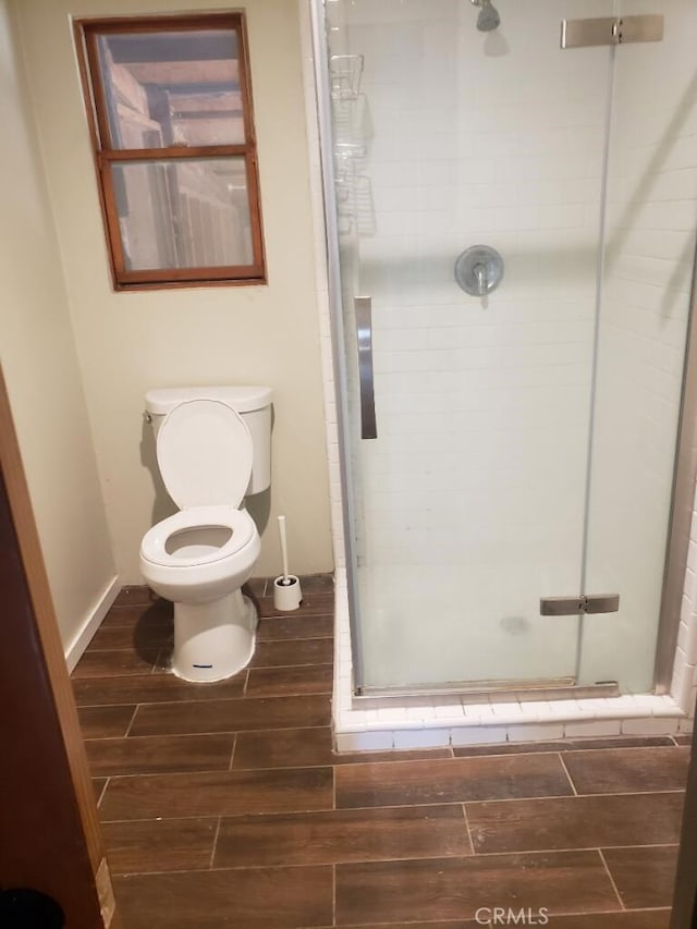 bathroom with toilet, wood tiled floor, and a shower stall