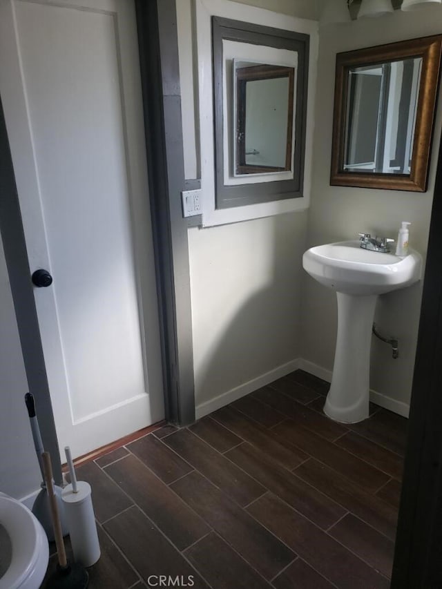 half bathroom featuring baseboards and wood finish floors