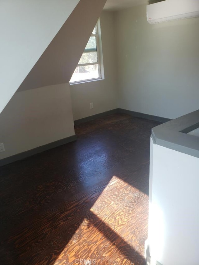 bonus room featuring a wall unit AC, dark wood-type flooring, and lofted ceiling