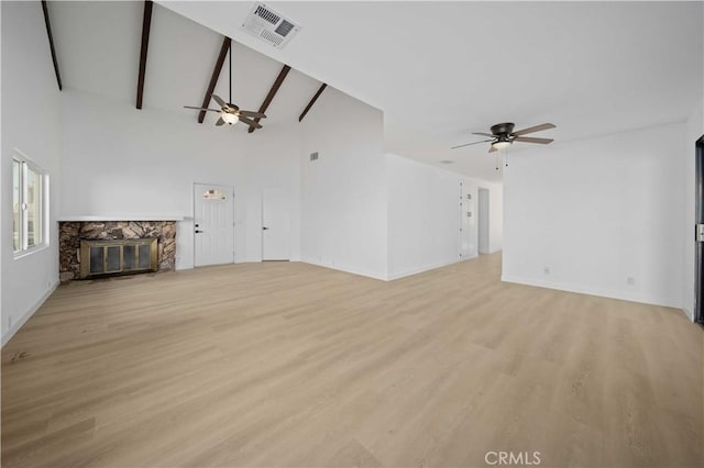 unfurnished living room featuring beam ceiling, ceiling fan, high vaulted ceiling, light hardwood / wood-style floors, and a fireplace