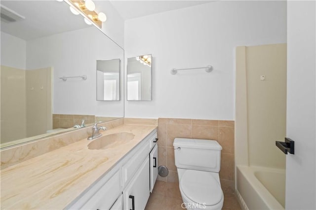 bathroom with tile patterned flooring, vanity, tile walls, and toilet