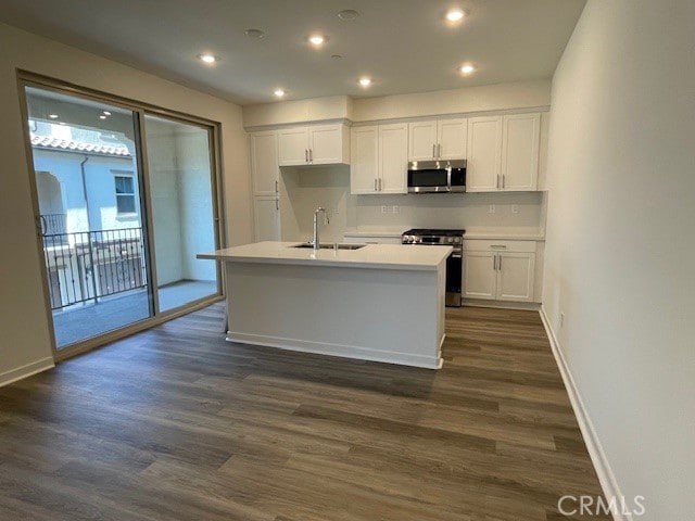 kitchen featuring a kitchen island with sink, dark hardwood / wood-style flooring, white cabinets, and appliances with stainless steel finishes