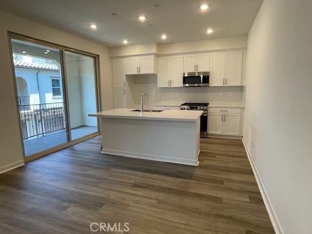 kitchen featuring stainless steel appliances, an island with sink, sink, and white cabinets