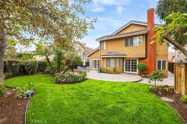 back of property featuring a yard, a chimney, stucco siding, a patio area, and fence private yard