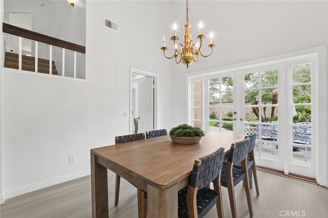 dining room featuring a notable chandelier, visible vents, baseboards, light wood-style floors, and french doors