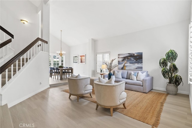 living room with baseboards, stairway, wood finished floors, an inviting chandelier, and high vaulted ceiling