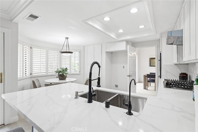 kitchen featuring under cabinet range hood, visible vents, a tray ceiling, and white cabinets