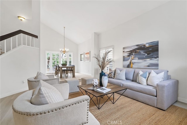 living room featuring baseboards, a chandelier, wood finished floors, stairs, and high vaulted ceiling