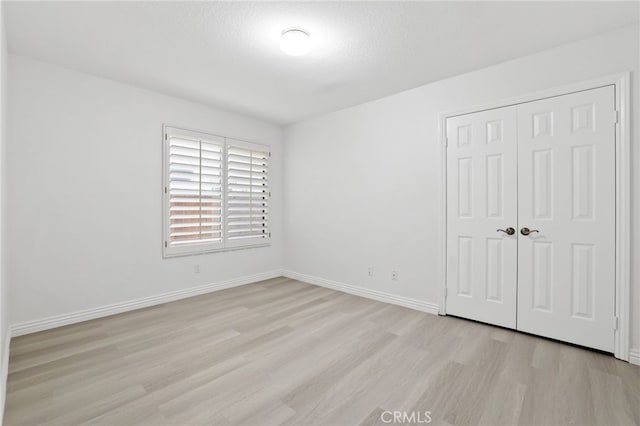 unfurnished bedroom featuring a closet, light hardwood / wood-style flooring, and a textured ceiling