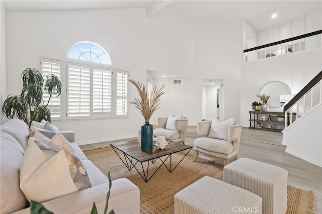 living room with beam ceiling, a wealth of natural light, high vaulted ceiling, and light wood-type flooring