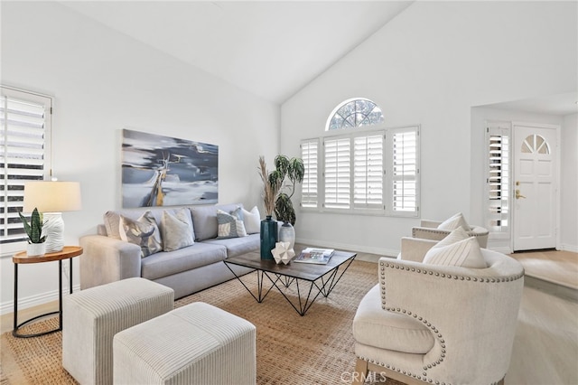 living room with baseboards, high vaulted ceiling, and wood finished floors