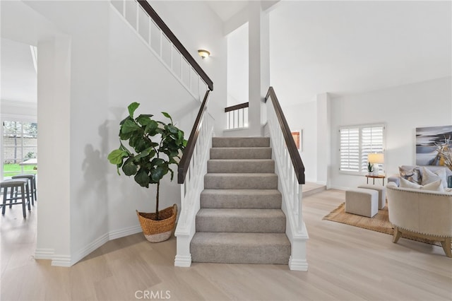 staircase featuring a healthy amount of sunlight, baseboards, and wood finished floors