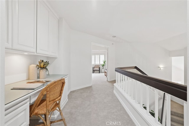 corridor featuring baseboards and light colored carpet