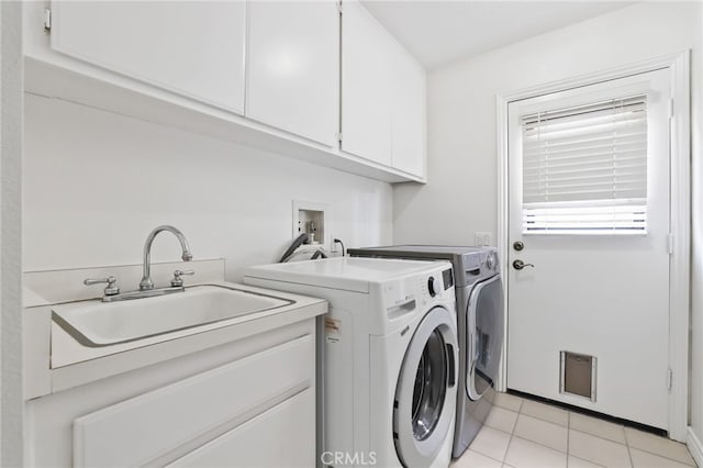 clothes washing area featuring light tile patterned floors, washing machine and clothes dryer, a sink, and cabinet space