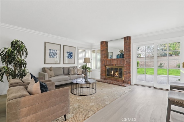 living area with a brick fireplace, crown molding, and wood finished floors