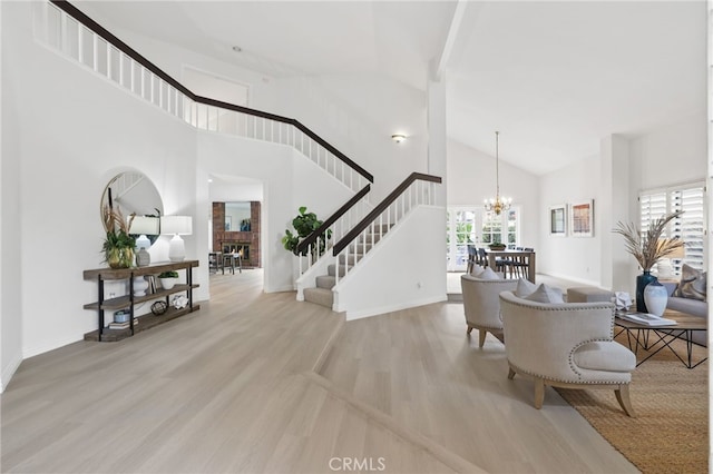 foyer entrance featuring a notable chandelier, high vaulted ceiling, and light wood-type flooring