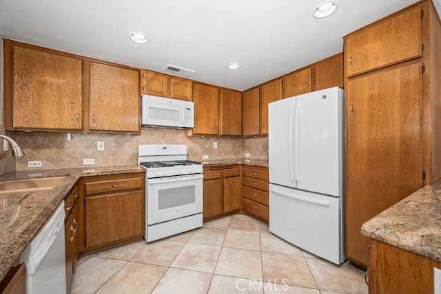 kitchen with light stone countertops, sink, light tile patterned floors, and white appliances