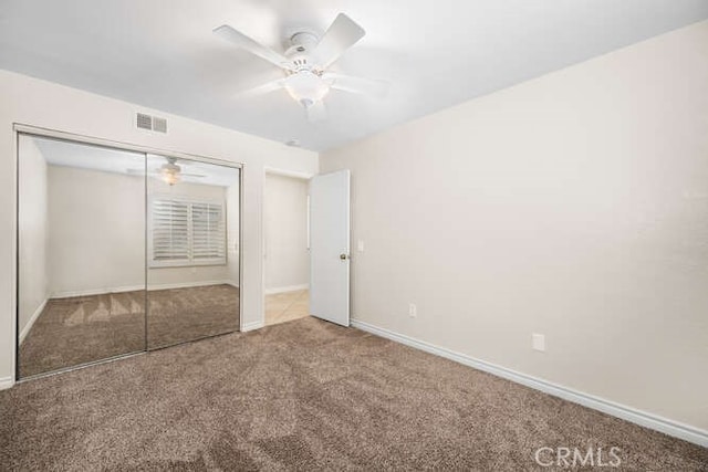 unfurnished bedroom with ceiling fan, a closet, and carpet floors