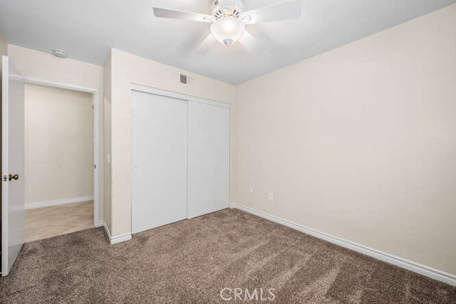 unfurnished bedroom featuring carpet flooring, ceiling fan, and a closet