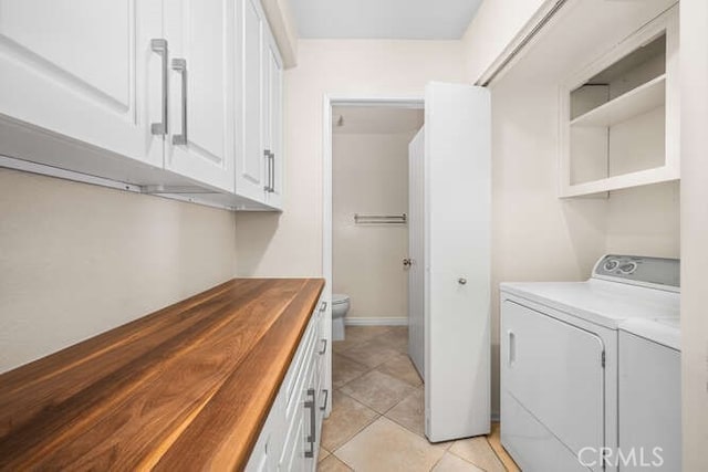 laundry area featuring washing machine and dryer, light tile patterned floors, and cabinets