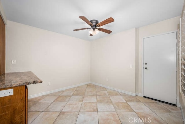 tiled empty room featuring ceiling fan