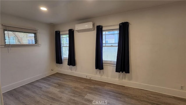 spare room with dark hardwood / wood-style flooring and an AC wall unit