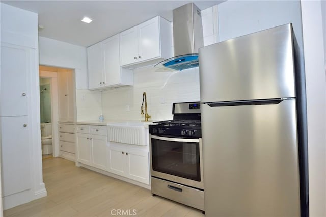 kitchen with white cabinetry, sink, wall chimney range hood, and appliances with stainless steel finishes