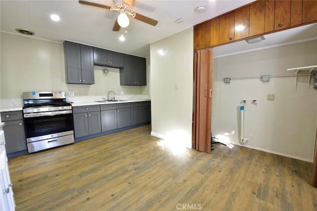 kitchen featuring ceiling fan, sink, dark wood-type flooring, stainless steel gas range oven, and gray cabinets