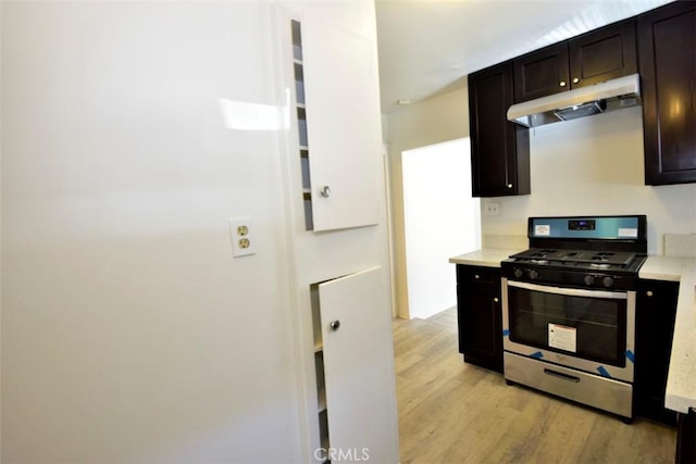 kitchen with dark brown cabinets, light wood-type flooring, and stainless steel gas range