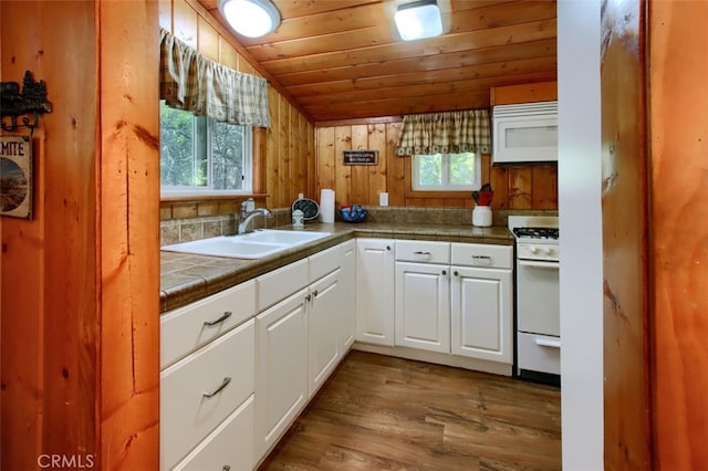 kitchen with white appliances, sink, white cabinets, hardwood / wood-style floors, and lofted ceiling