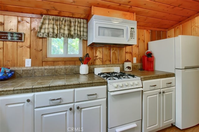 kitchen featuring wood walls, wooden ceiling, white appliances, white cabinets, and vaulted ceiling