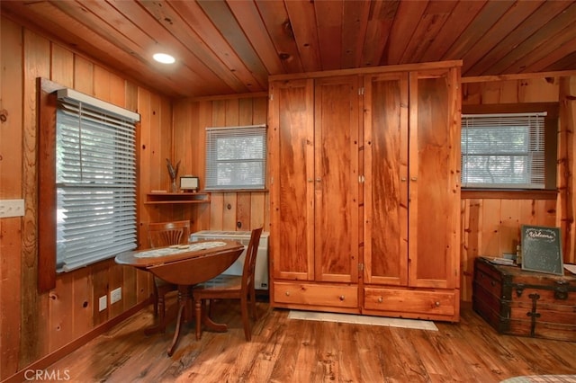 dining space with wood ceiling, wooden walls, and light hardwood / wood-style flooring