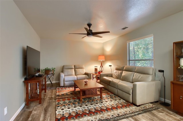 living room with a textured ceiling, hardwood / wood-style flooring, and ceiling fan