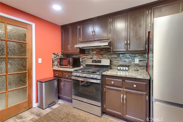 kitchen with stainless steel gas range, backsplash, refrigerator, light hardwood / wood-style floors, and dark brown cabinets