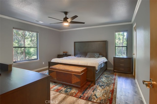 bedroom with a textured ceiling, ceiling fan, light wood-type flooring, and crown molding