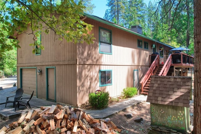 rear view of property with a garage and a deck