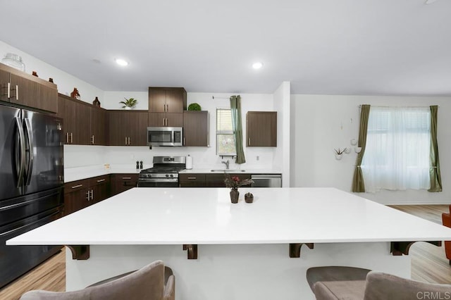 kitchen featuring a breakfast bar, sink, dark brown cabinets, a kitchen island, and stainless steel appliances