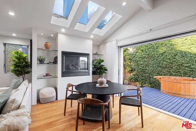 dining area with vaulted ceiling with beams and light hardwood / wood-style flooring