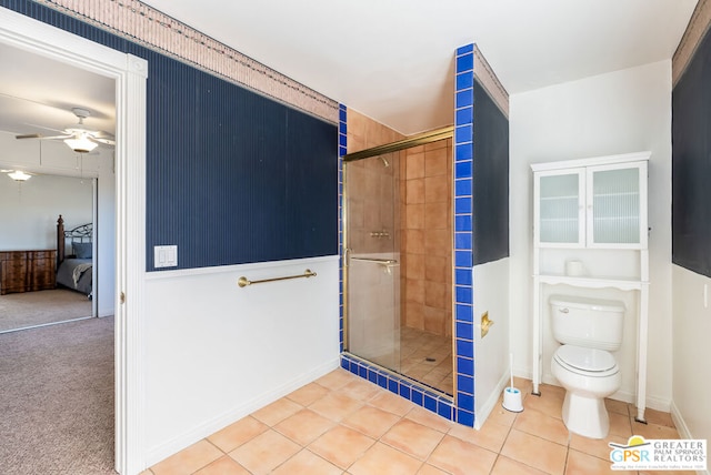 bathroom with tile patterned floors, ceiling fan, toilet, and an enclosed shower