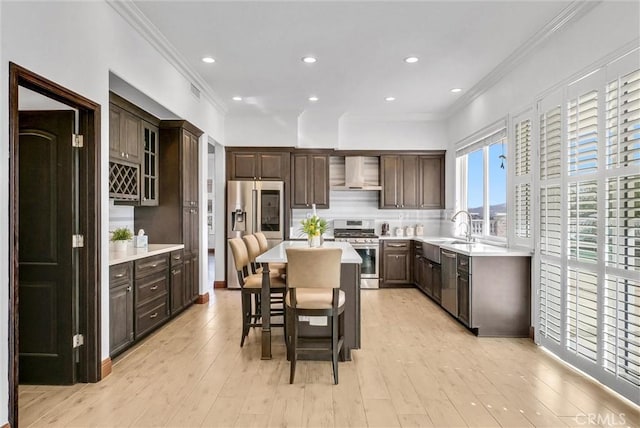 kitchen with stainless steel appliances, wall chimney range hood, a kitchen breakfast bar, backsplash, and a kitchen island