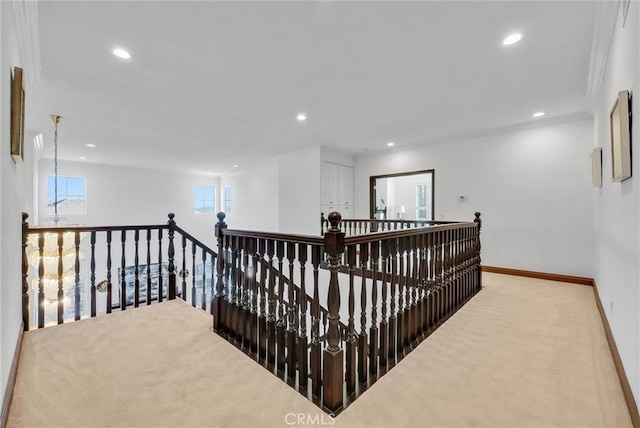 hall with crown molding, plenty of natural light, and light colored carpet